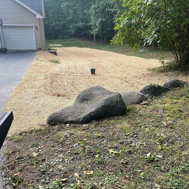 Lawn installation on side of driveway with large rock for decoration