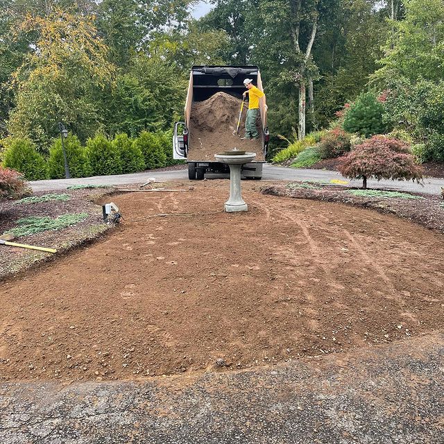 Grounds Guys professionals using dump truck to add dirt to landscape design for sod installation.