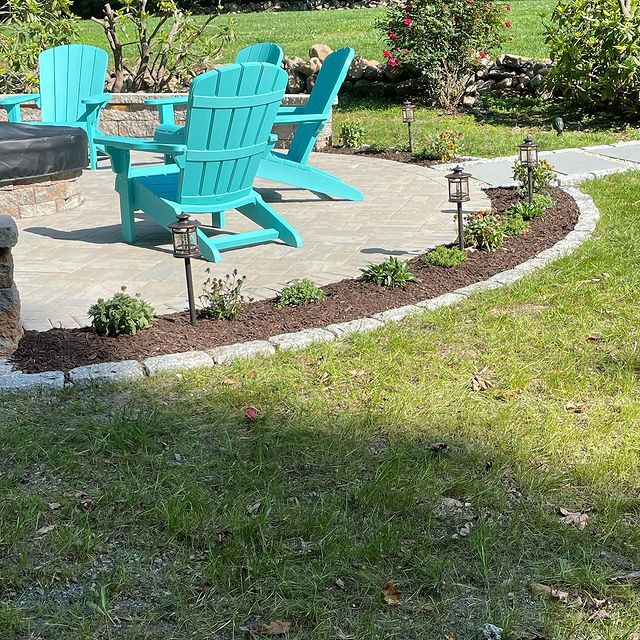 Beautiful seating area surrounded by small rock edged garden and green grass